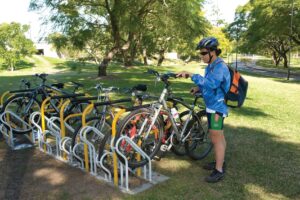 A cyclist parking a bike at a community bike rack in Queensland, part of local cycling initiatives.