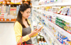 A person reading nutrition information on packaged food in a supermarket, promoting healthier and more informed choices.